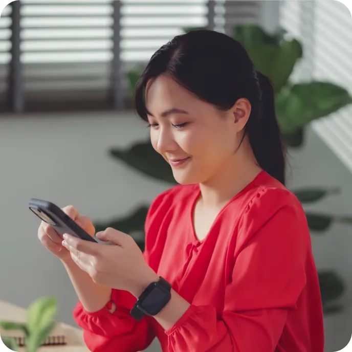 A woman in a red blouse smiling at her phone